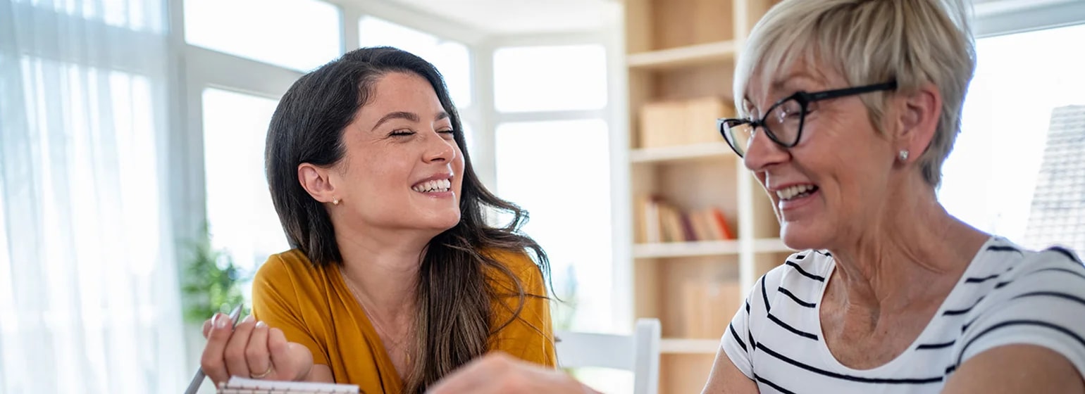 Zwei Personen sitzen am Tisch und planen gemeinsam Finanzen mit Notizblock, Münzen und Sparschwein – Symbolbild für langfristige Planung und Altersvorsorge für Selbständige.