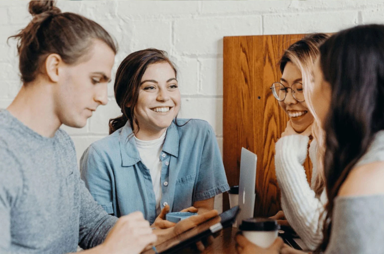 Vier junge Studierende arbeiten als freiberuflicher Student im IT‑Umfeld gemeinsam an Laptop und Tablet.
