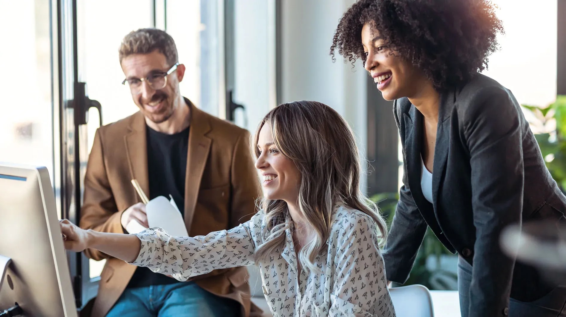 Eine Frau zeigt ihren beiden Arbeitskollegen auf dem Bildschirm einen passenden IT-Freelancer.