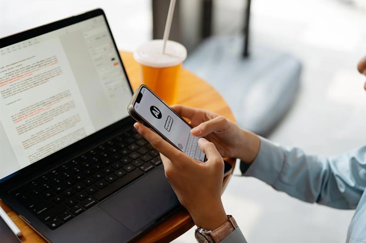 Person nutzt Smartphone und Laptop mit Text- und Analyseoberflächen auf einem Tisch – Symbolbild für den Einsatz von KI im Recruiting zur digitalen Bewerberkommunikation und -auswertung.