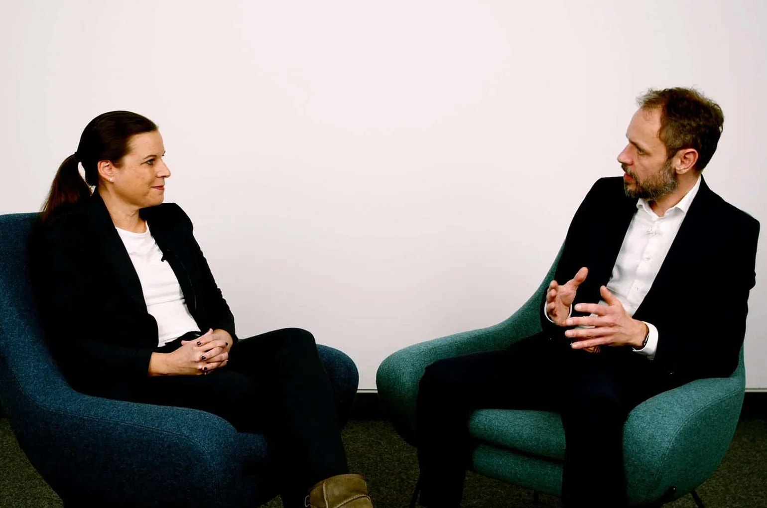 Frau und Mann sitzen in Sesseln und besprechen rechtliche Vorgaben zur Vermeidung von Scheinselbstständigkeit