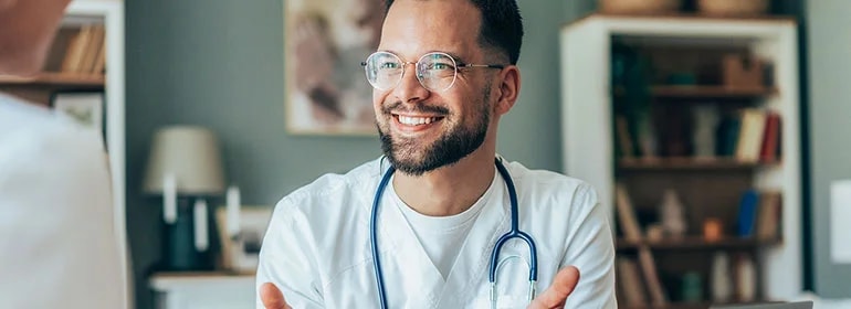 Arzt mit Stethoskop spricht mit einer selbständigen Person über Versicherungen.