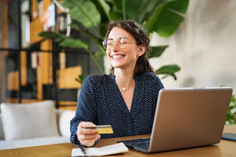 Person recherchiert am Laptop Altersvorsorge-Optionen für Selbstständige und hält dabei eine Bankkarte in der Hand.