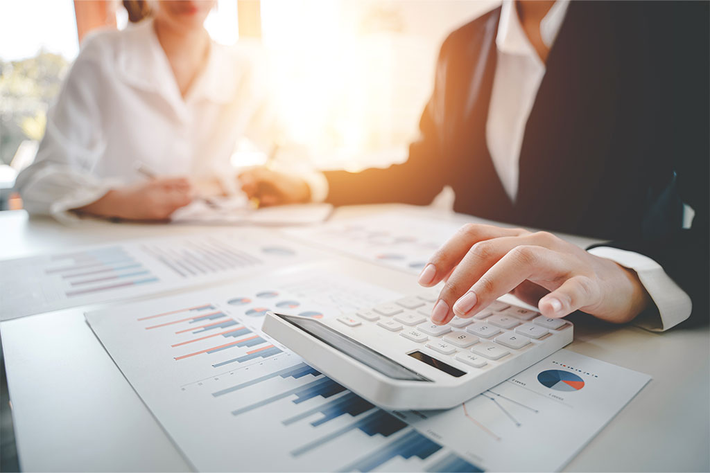 Finanzexperten berechnen persönliche Steuern für ihre Kunden mit Hilfe von Tabellen und einem Taschenrechner.